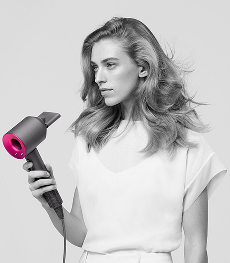 Девушка сушит волосы феном Dyson